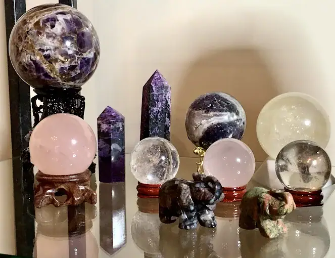 Various crystal spheres, towers, and animal figurines are displayed on a glass shelf, featuring amethyst, rose quartz, and clear quartz pieces. , The Goose Crown Inn