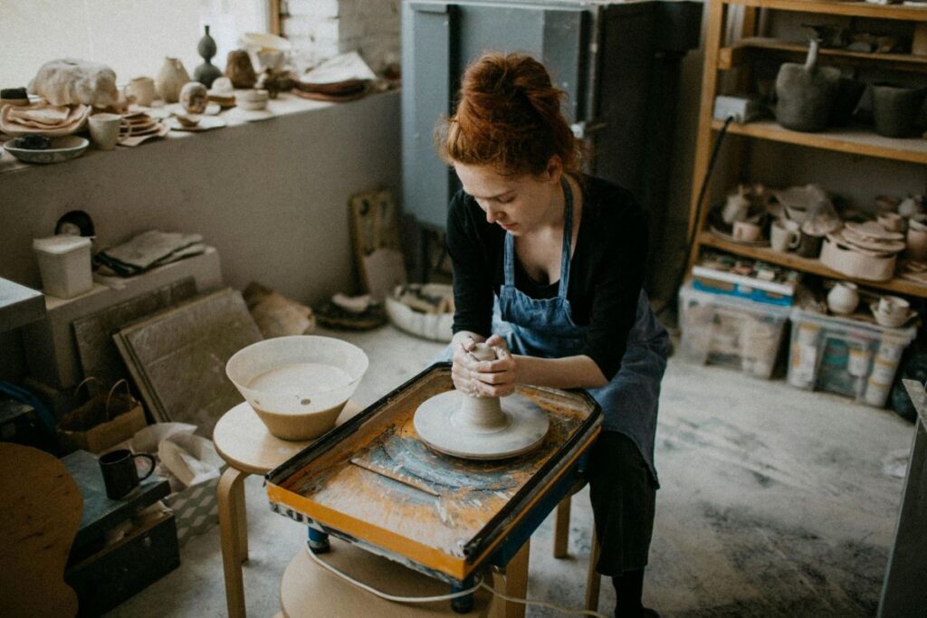 A woman works on a ceramics spinning wheel in a makers studio as part of the Stoughton arts scene; the Goose Crown Inn