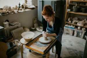 A woman works on a ceramics spinning wheel in a makers studio as part of the Stoughton arts scene; the Goose Crown Inn