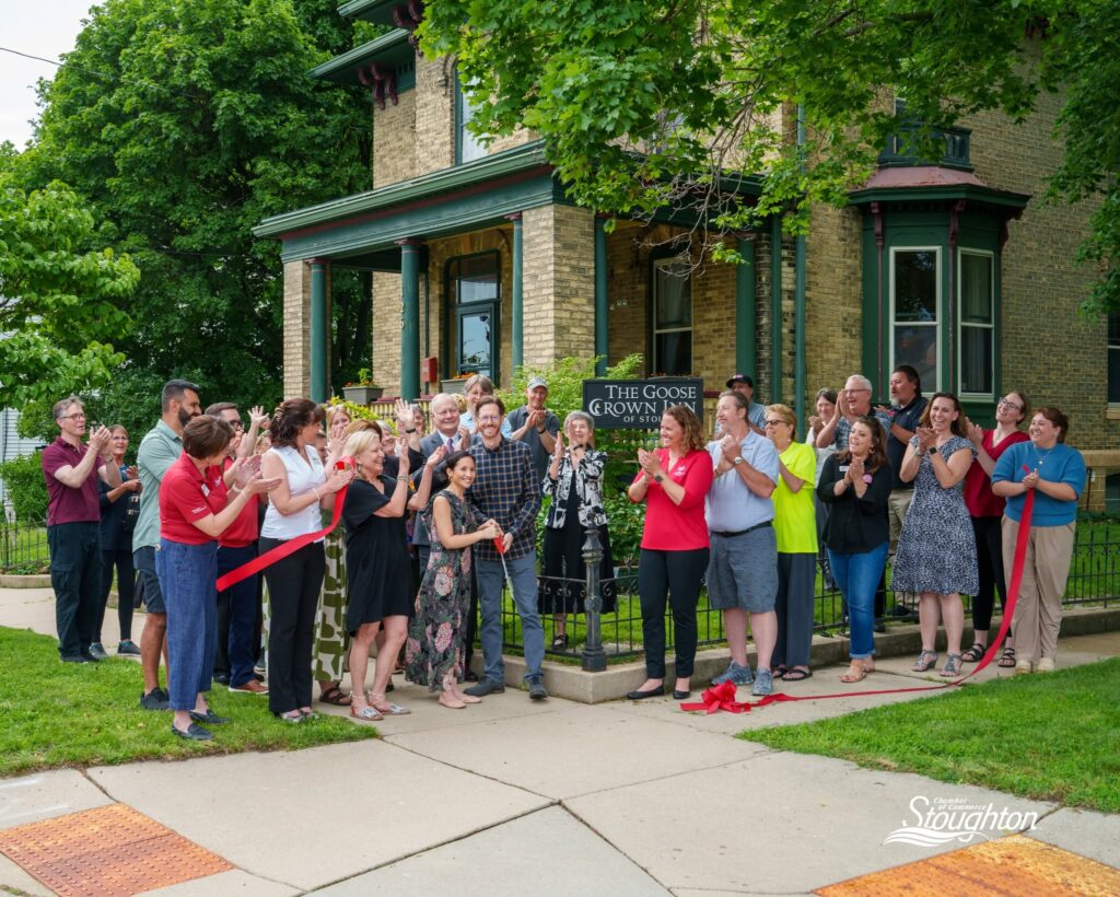 Ribbon cutting outside the Goose Crown Inn at the Naeset-Roe house in Stoughton, Wisconsin with a crowd of supporters.