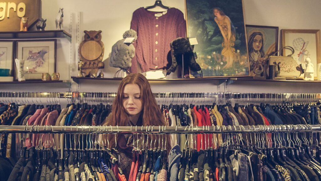 Thrift store in Stoughton WI with racks of vintage cloths and a female shopper perusing.