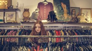 Thrift store in Stoughton WI with racks of vintage cloths and a female shopper perusing.