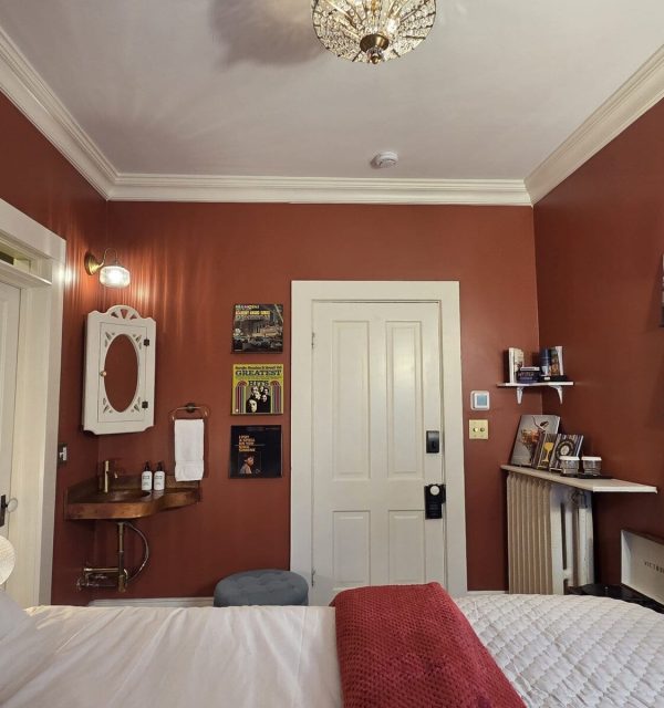 Stoughton inn guest room with copper sink, queen bed in foreground, a record player and vinyl LPS; the Goose Crown Inn