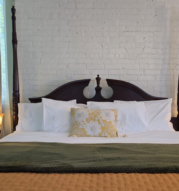 King bed against brick wall, sun room in suite of The Goose Crown Inn
